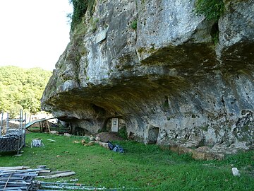 L'entrée de la grotte (porte blanche) sous la falaise de calcaire coniacien.