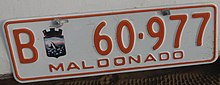 B60977 MALDONADO. Matrícula remolque caracteres y borde naranja con fondo blanco.