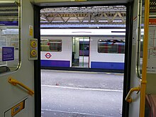 Double cross platform interchange looking from one train through another train (which has its doors open on both sides) to reveal a third train at Barking in London Barking-London-Double-Cross-Platform-Interchange.jpg