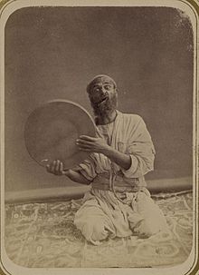 A traditional Central Asian musician from the 1860s or 1870s, holding up his dayereh.