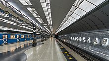 Un grand quai central avec un métro bleu à quai.