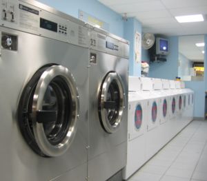Image shows a line of washing machines in a laundromat.