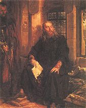 A bearded monk, sitting by a window with a document in his hands