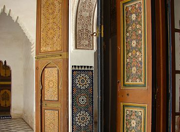 Una varietà di stili vernacolari decorativi islamici in Marocco: pannelli di legno simil-girih, piastrelle zellige, stucchi, calligrafia e pannelli su porta floreali