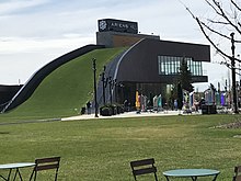 Photo showing Arien's Hill, a grassy hill which is built against the side of a two-story building