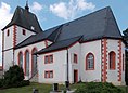 Das Foto zeigt eine alte Kirche mit Schieferdach. Sie ist weiß angestrichen, die Fenstereinfassungen und Gebäudeecken sind in rot hervorgehoben.