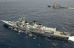 Long grey ship seen from above, with a smaller ship in the background