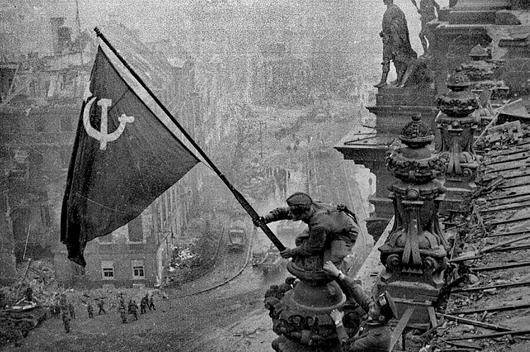 Солдаты устанавливают флаг СССР на крышу Рейхстага в Берлине, май 1945
