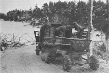 Soldiers sprinkle sand on the road from a truck