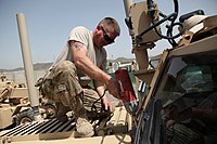 A Seabee, assigned to Construction Battalion Maintenance Unit 202, conducts maintenance on a Cougar HE 6x6, at Forward Operating Base Salerno, Khost province, Afghanistan. U.S. Navy Construction Mechanic 1st Class William Cook, assigned to Construction Battalion Maintenance Unit 202, attached to the Khost Provincial Reconstruction Team, unbolts the windshield from a Cougar H 6x6 120811-A-PO167-009.jpg