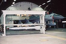 Weapons Storage and Security System vault in raised position holding a B61 nuclear bomb, adjacent to an F-16. The vault is within a Protective Aircraft Shelter. B61 in Weapons Storage and Security System.jpg