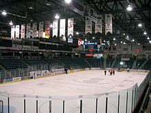 Photo of ice rink with team banners hanging from the ceiling