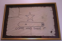 Белый флаг с пятиконечной звездой над очертанием маленькой пушки и надписью «Приди и забери это» внизу. Левый угол флага оторван и пришит.
