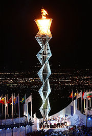 Opening ceremonies climax with the lighting of the Olympic Flame. For lighting the torch, modern games feature elaborate mechanisms such as this cauldron-spiral-cauldron arrangement lit by the 1980 U.S. Olympic ice hockey team at the 2002 Winter Olympics.
