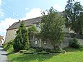 Wohnstallhaus eines Bauernhofes, dazu Hofmauer mit vermauertem Torbogen und Pforte, weiterhin ein in der Stützmauer vermauertes Steinkreuz