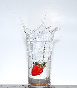 Une fraise tombant dans un verre d'eau sous l'effet de la gravité. L'impact de la fraise sur l'eau a brisé la tension superficielle et projette des gouttes à l'extérieur du verre. (définition réelle 1 694 × 1 943)