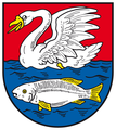 Дзьобатий плавець У червоному полі на синій хвилі пливе срібний лебідь із золотим дзьобом, в якій під яким пливе срібна риба із золотим озброєням. Місто Нахтерштедт, Німеччина.