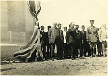 a group of people standing at attention next to a memorial while a person blows a bugle