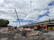 Construction site with cranes and construction equipment with a concrete railway viaduct on the right