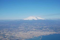 Tanaw sa himpapawid ng metropolitanong lungsod na nakapalibot sa Catania. Ang Bundok Etna ay ang bundok sa malayo.