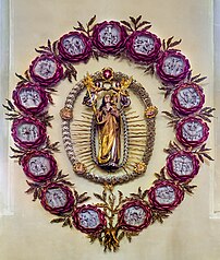 Notre-Dame du Rosaire, en l'église Sainte-Marie-du-Rosaire de Gerolzhofen, en Bavière. La Vierge à l'Enfant y est représentée en majesté, couronnée par deux anges, et entourée d'un chapelet dont les gros grains représentent les 5 plaies du Christ. Le tout est contenu dans un collier de médaillons en forme de roses, dont chacun représente l'un des 15 principaux mystères du Rosaire. (définition réelle 6 030 × 7 109)