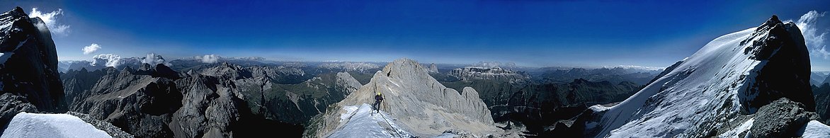 Panoramica dalla cresta ovest della Marmolada. All'orizzonte, a destra e sinistra di Punta Penia, le Pale di San Martino, il Latemar, il Catinaccio, il Sassolungo, il Sella e le Dolomiti Ampezzane.