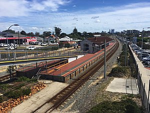 View of the station platform from a footbridge. The station has a large brick building on the platform to provide shelter.