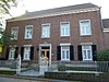 Bakstenen herenhuis met verdieping en zadeldak. Gevel van vijf traveeën met ingang en vensters in Naamse steen