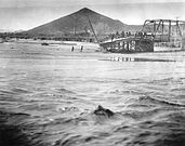 Un puente destruido sobre el Santa Cruz durante la inundación de 1915. La montaña "A" al fondo.