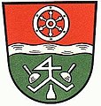 Landkreis Miltenberg (–1972) Geteilt durch einen silbernen Wellenbalken von Rot und Grün; oben ein sechsspeichiges silbernes Rad, unten ein von drei im Dreipass angeordneten silbernen Steinmetzgeräten umgebenes silbernes Zunftzeichen.