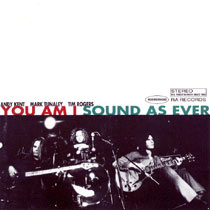 The top half of the cover is a simple white rectangle with text at about the middle of the front cover. The band's members are named in small, black, block capitals at left. The group's name is immediately below in larger, red, block capitals and followed by the album title in similar sized but blue, block capitals. Additional text in grey, block capitals is placed at right: Stereo The finest in rock since 1992 in a rectangle; the catalogue number 74321439652 in an oval; and the record label RA Records. For the bottom half there is a black-and-white photo of three men and their instruments. The man at left is seated, playing a bass guitar, his eyes appeared closed, he wears his hair over shoulder length which partly covers his left eye. The second man leans on his drum kit with both hands, on a drum and his head is close to it. He wears curly, hair and is looking down and towards the bass guitarist. Microphones are placed in front of his kit. The third man is also seated, but plays a lead guitar, cradled across his lap while staring off to his left and up. There are two stage lights visible. A can of beer is in front of the bass drum.