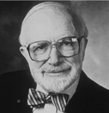 A black and white photo of an older man with glasses wearing a bow tie.