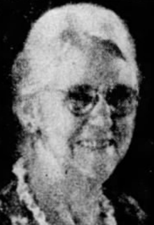 An older white woman, smiling, wearing glasses.