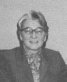 An older white woman wearing glasses and a business suit.