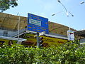 A typical road sign in Kuala Lumpur, with yellow letters for major thoroughfares and green letters on white background for parks and locations of interests. Smaller signs below it show directions for pedestrians and tourists.