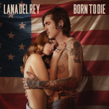 Del Rey and a tattooed man embrace topless in front of the American flag.