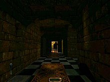 A long, darkened stone hallway with a light at the far end, against which a figure is silhouetted. Carpet is placed down the middle of the black-and-white tiled floor, and a black object protrudes from the bottom right corner of the image.