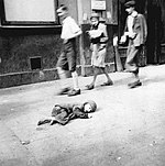 A child dying in the streets of the crowded Warsaw Ghetto, where hunger and disease was endemic.