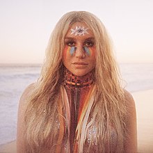 Kesha with various colors painted on her face and neck.