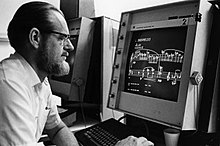Leland Smith in front of a computer terminal with music displayed on screen