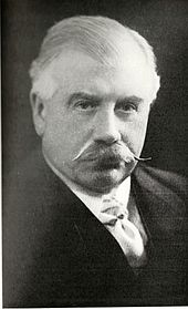 head and shoulders photograph of a middle-aged man with large, curled moustache