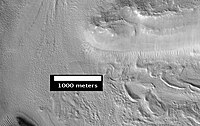 Smooth cliff of the Mamers Valles. Note the lack of boulders. Much of the surface may have just been blown in or dropped from the sky (as dirty frost). Image from HiRISE.