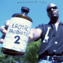 Brown holding a medicine bottle with a hand-written label that says "Erotic Probiotic 2" on it