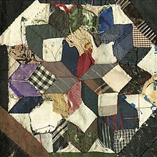 A fraying quilt with a geometric design. The design is made of square and rhombic patches of different fabrics forming, altogether forming an octagon.