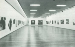 An archival black-and-white photo of rows of paintings hung in a white-cube gallery space