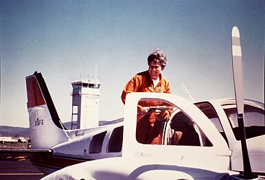 Photo of Mary Barr standing on the wing of her transport plane, 1975