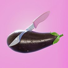 An eggplant being cut by a knife on a pink background.