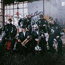 The cover artwork for "(Nendest) narkootikumidest ei tea me (küll) midagi". The cover features members of both groups of the song in a group photo and their instruments with a graffiti-splattered wall serving as the background.