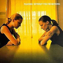 The album cover features two women sitting on a table in front of each other, looking down at the table. The light coming in from the curtains makes a yellow colour.