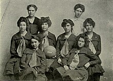 Black-and-white team photo of the 1903 KU women's basketball team with the center-most girl holding a basketball with "1903" painted on it